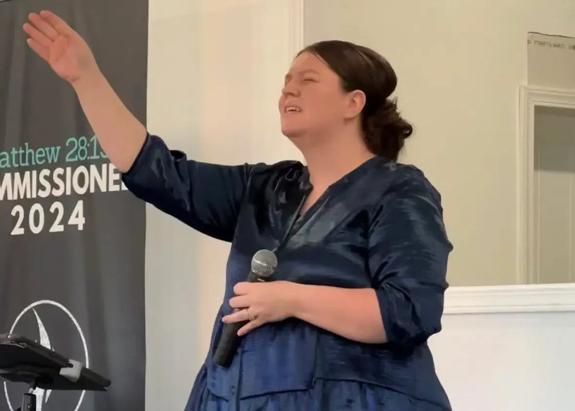 Woman lifting her hand in worship while leading The Pentecostals of Cody during service
